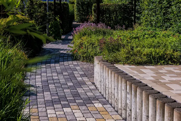 Gepflegte Gartenanlage mit gepflastertem Weg und Bepflanzung